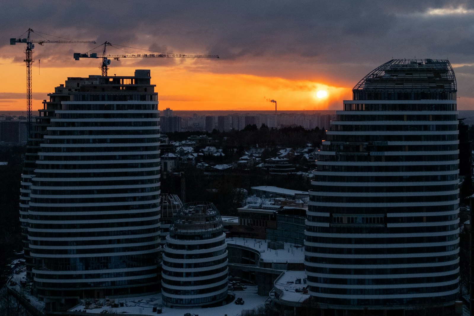 Modern architectural building under construction with cranes at dusk